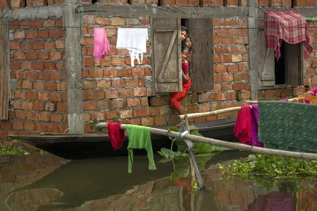 People look out from the window of their flooded house in Tarabari village, in the northeastern Indian state of Assam, Monday, June 20, 2022. (Photo by Anupam Nath/AP Photo)
