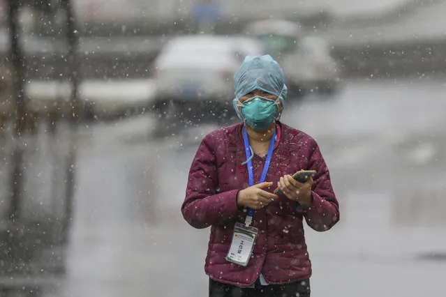 A goverment worker wearing a face mask waits for patients to arrive at a tumor hospital newly designated to treat COVID-19 patients in Wuhan in central China's Hubei Province, Saturday, February 15, 2020. (Photo by Chinatopix via AP Photo)