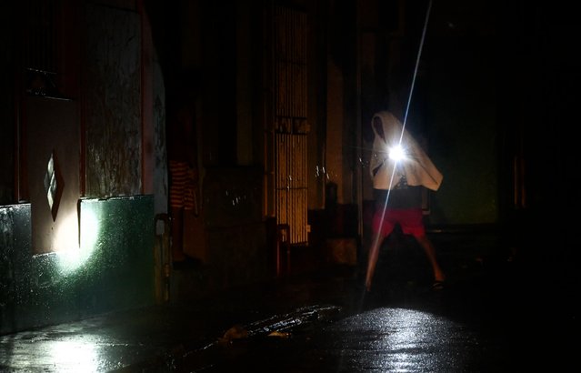 A man walks with a torchlight on a darkened street due to a blackout after the pass of hurricane Rafael in Havana, on November 6, 2024. Hurricane Rafael left Cuba on Wednesday night, leaving the island in darkness with widespread power outages and destruction in some villages after hitting as a powerful Category 3 hurricane. (Photo by Yamil Lage/AFP Photo)