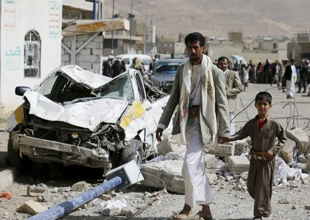 A man and his son walk past a car destroyed by Saudi-led air strikes on the nearby offices of the education ministry's workers union in Yemen's northwestern city of Amran August 19, 2015. (Photo by Khaled Abdullah/Reuters)