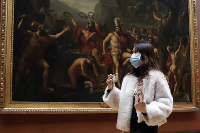 Masked tourist walks by an oil on canvas of 1814 entitled Leonidas at Thermopylae, by Jacques Louis David, at the Louvre Museum in Paris, Thursday, March 5, 2020. With the COVID-19 virus taking firmer hold in Europe, the continent is facing the same complications seen in Asia weeks ago. (Photo by Francois Mori/AP Photo)