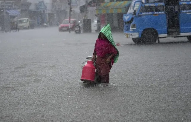A woman wades through a waterlogged street during heavy rainfall in Jammu, India, Thursday, July 28, 2022. India's monsoon season runs from June to September. (Photo by Channi Anand/AP Photo)