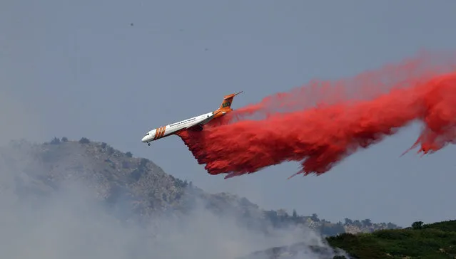 A heavy tanker drops retardant on a wildfire in Weber Canyon, Tuesday, September 5, 2017, near Ogden, Utah. At least one home went up in smoke and more than 1,000 people were evacuated as high winds fed the flames that started in a canyon north of Salt Lake City. (Photo by Rick Bowmer/AP Photo)