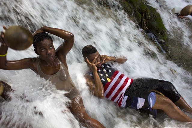 Voodoo pilgrims bathe in a waterfall believed to have purifying powers during the annual celebration in Saut d' Eau, Haiti, Saturday, July 16, 2016. Annually, the falls are the site of a large, important religious pilgrimage, during the festival of Our Lady of Carmel, from July 14–16. A Eucharistic rite is held during the festival, as well as various vodou rituals, but the penultimate devotional activity is bathing in the waters of the falls, and asking favors of the Virgin or Erzulie. After bathing, voodoo pilgrims throw away the dresses they wore to the site, and don new clothes for good luck. (Photo by Dieu Nalio Chery/AP Photo)