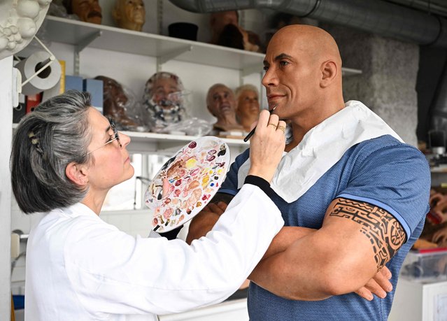 An employee adjusts the skin tone on the wax effigy of Dwayne Johnson, after the US actor complained about its pale skin tone, at the Grevin museum in Paris on October 24, 2023. Johnson, who is of Samoan and Black origin, took to Instagram this weekend to joke about the Grevin Museum's botched wax figure, which appeared to depict him with white skin, and bears only a vague likeness to his features. (Photo by Stefano Rellandini/AFP Photo)