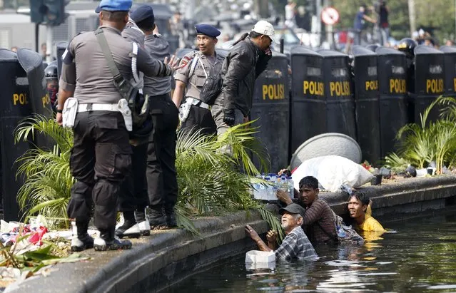 People take shelter in a fountain after Indonesian police used tear gas and water cannon to disperse supporters of presidential candidate Prabowo Subianto near the Constitutional Court in Jakarta August 21, 2014. Indonesian police fired tear gas to disperse thousands of protesters outside the country's top court in Jakarta on Thursday, as judges started delivering their verdict into last month's disputed presidential election. (Photo by Darren Whiteside/Reuters)