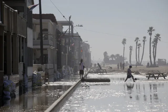 A man walks through the flooded beachfront properties on Wednesday, August 27, 2014, in Seal Beach, Calif. (Photo by Jae C. Hong/AP Photo)