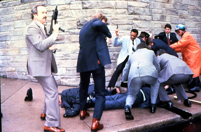 James Brady and a police officer are seen lying on the ground after being shot while the suspect John Hinckley Jr. is apprehended,at right, moments after the attempted assassination of President Ronald Reagan, Washington, DC, March 30, 1981. (Photo by Dirck Halstead/Getty Images)