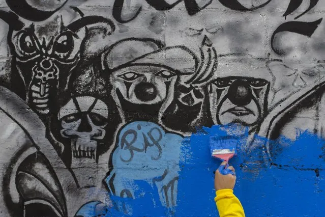 In this June 21, 2016 photo, an inmate paints over Mara Salvatrucha gang graffiti in the April 22 neighborhood in Soyapango, El Salvador. After becoming the world's murder capital last year and posting an equally bloody start to 2016, El Salvador has seen its monthly homicide rates fall by about half. The government attributes the drop to a tough military crackdown on the country's powerful gangs, while the gangs themselves claim credit for a nonaggression pact between the three biggest criminal groups. (Photo by Salvador Melendez/AP Photo)
