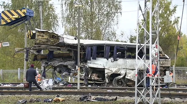 In this video grab provided by the RU-RTR Russian television via APTN, Russian Emergency Situation employees work at the scene of a derailment at a railway crossing near in the town of Pokrov, about 85 kilometers (53 miles) east of Moscow, Russia. Uzbekistan's Foreign Ministry says that 19 citizens of the ex-Soviet nation were killed when a train slammed into a bus carrying them near Moscow. (Photo by RU-RTR Russian Television/ APTN via AP Photo)