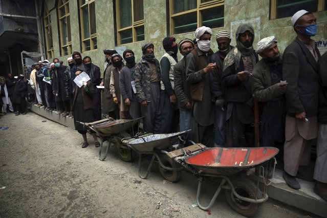 Daily-wage workers wait in line to receive free wheat donated by Afghan businessmen ahead of the upcoming holy fasting month of Ramadan in Kabul, Afghanistan, Monday, April 20, 2020. Muslims across the world are observing the holy fasting month of Ramadan, when they refrain from eating, drinking and smoking from dawn to dusk. (Photo by Rahmat Gul/AP Photo)