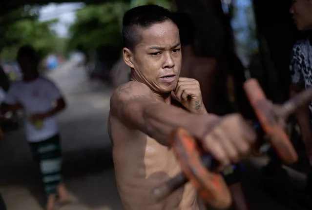 In this Wednesday, July 15, 2015, photo, a member of the White New Blood lethwei fighters club, a Myanmar traditional martial-arts club which practices a rough form of kickboxing, practices strengthening exercises during a practice session at their gym on a street in Oakalarpa, north of Yangon, Myanmar. (Photo by Gemunu Amarasinghe/AP Photo)