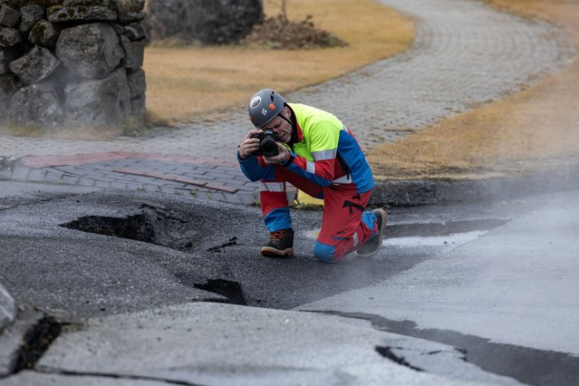 A member of search and rescue team takes pictures of a smoke rising from the crack in a road in the fishing town of Grindavik, which was evacuated due to volcanic activity, in Iceland on November 15, 2023. (Photo by Marko Djurica/Reuters)