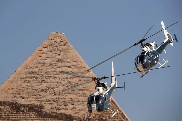 Hel Gazelle helicopters of the Egyptian Air Force's “Horus” aerobatic team perform during the Pyramids Air Show 2022 by the Pyramid of Khafre at the Giza Pyramids Necropolis on the southwestern outskirts of the Egyptian capital on August 3, 2022. (Photo by Mahmoud Khaled/AFP Photo)