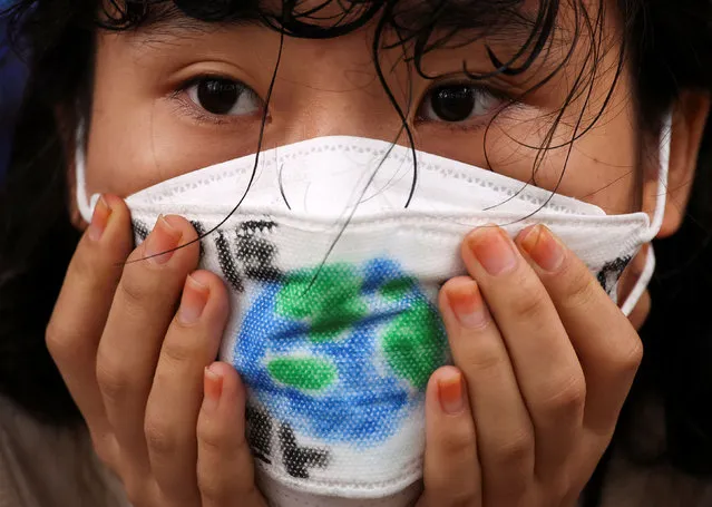A girl wears a face mask with a drawing of the earth as she takes part in a global climate protest near the presidential office in Seoul, South Korea on September 23, 2022. (Photo by Kim Hong-Ji/Reuters)