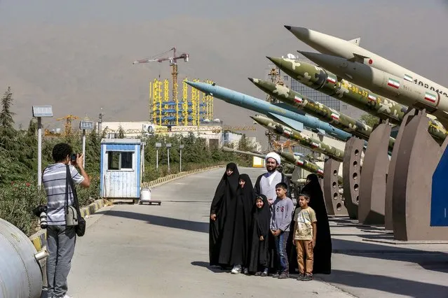 Iranian photographer Arash Khamooshi takes a photograph of cleric Mohammad Kalbasi and his family as they visit an exhibition on the 1980-88 Iran-Iraq war, at a park, northern Tehran, Iran, Thursday, Sept. 25, 2014. (Photo by Vahid Salemi/AP Photo)