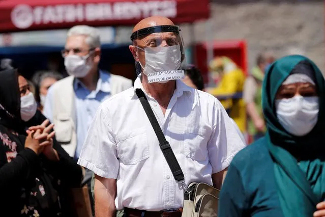 Mehmet Usta, a 74-year former marathon runner wearing a protective masks and a face shield maintains social distance due to the coronavirus disease (COVID-19) outbreak, while waiting in line to enter a park, as senior citizens are not allowed to go out of their houses except six hours on Sundays, in Istanbul, Turkey, June 7, 2020. Writing in his face shiled reads that: “Yes to face mask, social distancing, fine. No to staying at home”. (Photo by Murad Sezer/Reuters)