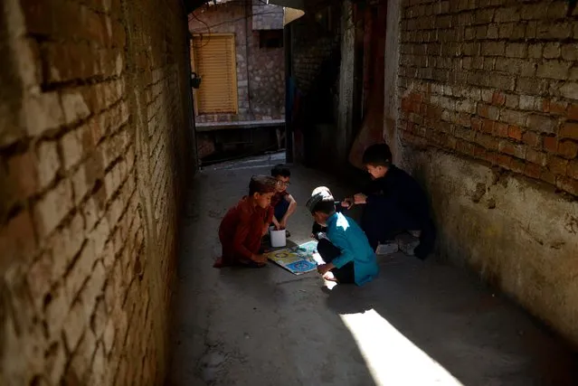 Children play Ludo game on a street during a government-imposed nationwide lockdown as a preventive measure against the COVID-19 coronavirus, in Rawalpindi on May 5, 2020. Asian markets suffered steep losses after Donald Trump sparked fears of a renewed trade war with China over its role in the coronavirus pandemic. (Photo by Farooq Naeem/AFP Photo)