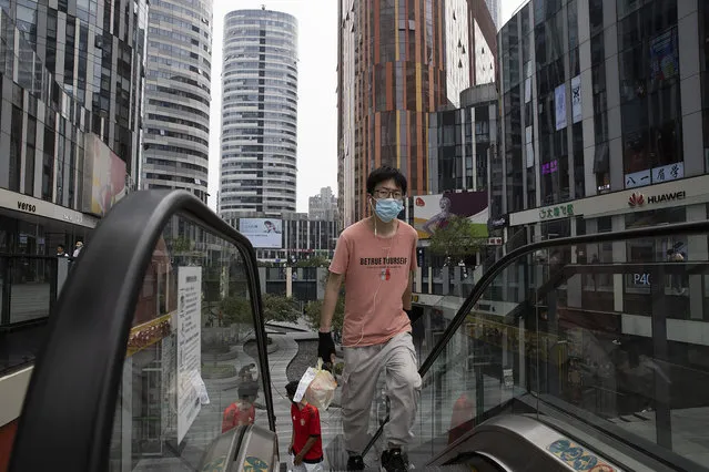 A man wearing a face mask to curb the spread of the coronavirus carries a take away order of food along a popular retail street in Beijing on Tuesday, June 9, 2020. (Photo by Ng Han Guan/AP Photo)