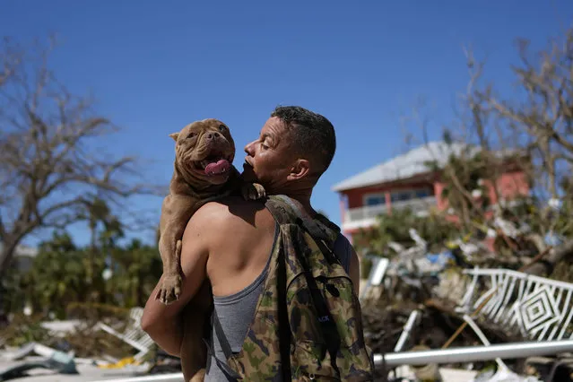 Eduardo Tocuya carries a dog he recovered in hopes of reuniting it with its owners, two days after the passage of Hurricane Ian, in Fort Myers Beach, Fla., Friday, September 30, 2022. (Photo by Rebecca Blackwell/AP Photo)