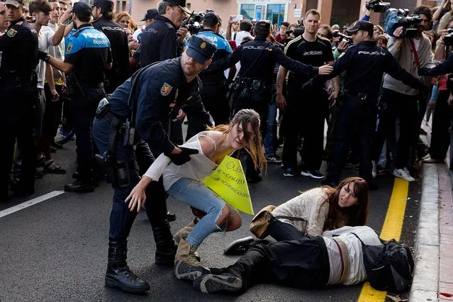 A riot policeman moves an animal activist who was trying to help her friend who was injured during clashes with police as they tried to stop a van carrying Excalibur, the dog belonging to Ebola victim Maria Teresa Romero Ramos, which the Spanish authorities want to put down, outside the nurse's private residence on October 8, 2014 in Alcorcon, Spain. (Photo by Gonzalo Arroyo Moreno/Getty Images)