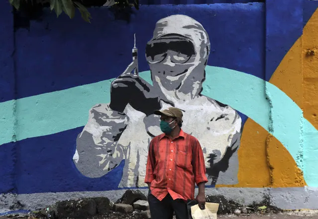 A man stands in front of a graffiti honoring those in the frontlines in the fight against the coronavirus in Mumbai, India, Tuesday, July 7, 2020. India has overtaken Russia to become the third worst-affected nation by the coronavirus. After a strict nationwide lockdown, India has eased restrictions in most of the country except for the highest-risk areas. (Photo by Rajanish Kakade/AP Photo)