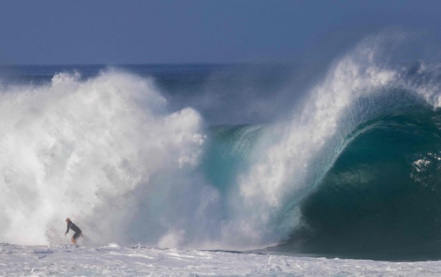 US surfer John John Florence rides a huge swell in training for the Da Hui Backdoor Shootout 2025 event held annually at Pipeline on the North Shore of Oahu, Hawaii, on December 26, 2024. The “Da Hui Backdoor Shootout” in 2025 is an invitation-only surfing competition held on the North Shore of Oahu, Hawaii, during a holding period from January 4 to 16, 2025. (Photo by Brian Bielmann/AFP Photo)