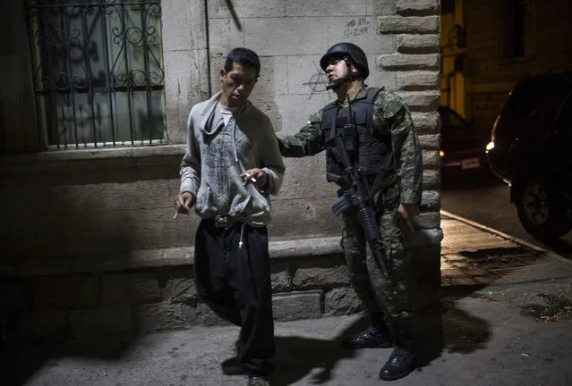 A military police officer orders a bystander to leave the streets during the second day of a  government imposed dawn-to-dusk curfew in Tegucigalpa, Honduras, late Saturday, December 2, 2017. The main opposition candidate called Saturday for Honduras' disputed presidential election to be held again after the country erupted in deadly protests over the delayed vote count. (Photo by Rodrigo Abd/AP Photo)