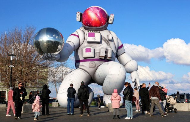 People gather in a square to look at a giant inflatable in the shape of a cosmonaut installed ahead of Cosmonautics Day, which is widely celebrated in Russia on April 12 to mark the anniversary of Yuri Gagarin's historic first human space flight in 1961, in the Black Sea port city of Yevpatoriya, Crimea, on April 9, 2025. (Photo by Alexey Pavlishak/Reuters)