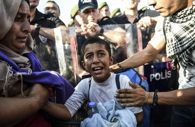 A boy cries as Syrian refugees and migrants push against a police barricade as they march along the highway towards the Turkish-Greek border at Edirne on September 18, 2015. Several hundred migrants who have been blocked by police in northwest Turkey from crossing overland into Greece drew closer to the border after the authorities briefly opened the route. (Photo by Bulent Kilic/AFP Photo)