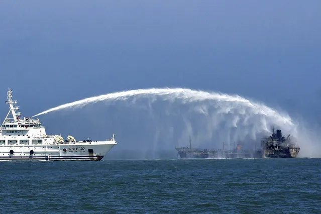 In this photo released by Donghai Rescue Bureau via Xinhua News Agency, a rescue vessel tries to put out fire emerging from an oil tanker after it collided with a cargo ship near the Yangtze River estuary off Shanghai, Thursday, August 20, 2020. More than a dozen sailors were missing Friday, Aug. 21, 2020 after two ships collided in the Yellow Sea east of Shanghai, Chinese authorities reported. (Photo by Donghai Rescue Bureau/Xinhua via AP Photo)