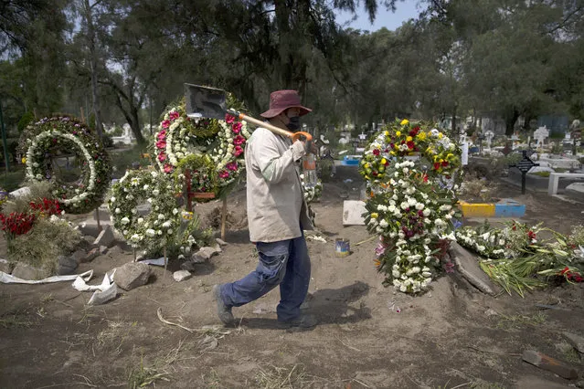 A grave digger walks in the COVID-19 section of the cemetery of San Lorenzo Tezonco Iztapalapa on the outskirts of Mexico City, Tuesday, September 1, 2020. (Photo by Marco Ugarte/AP Photo)