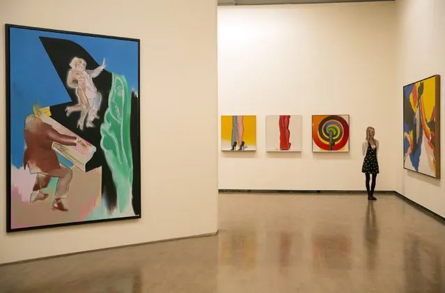 A gallery assistant poses amongst paintings during a media viewing of the “Allen Jones RA” at the Royal Academy of Arts in London November 11, 2014. (Photo by Neil Hall/Reuters)