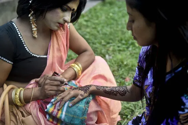 A Bangladeshi hijra – transgender – (L) applies henna on a woman's hand as a part of the first ever nationwide program to observe “Hijra Day” to be held on November 10, in Dhaka on November 9, 2014. On November 10, 2013, the Bangladesh government officially recognised hijras as a separate gender in order to secure their rights, enabling them to identify their gender as “hijra” on all government documents, including passports. (Photo by Munir Uz Zaman/AFP Photo)