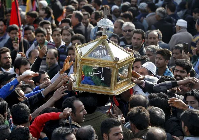 Kashmiri Shi'ite Muslim mourners touch a glass case containing a copy of the Koran during a Muharram procession ahead of Ashura in Srinagar October 21, 2015. Ashura, which falls on the 10th day of the Islamic month of Muharram, commemorates the death of Imam Hussein, grandson of Prophet Mohammad, who was killed in the 7th century battle of Kerbala. (Photo by Danish Ismail/Reuters)