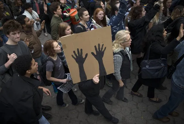 A man marches with a sign depicting raised hands as students and activists hold a protest march through the streets of Manhattan against the verdict announced in the shooting death of Michael Brown, in New York, December 1, 2014. (Photo by Mike Segar/Reuters)