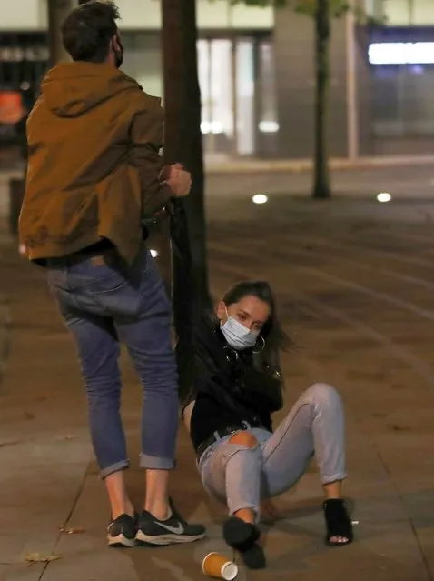 A man helps lift a woman off the ground the night before a local lockdown amidst the spread of the coronavirus disease (COVID-19) in Manchester, Britain on October 22, 2020. (Photo by Molly Darlington/Reuters)