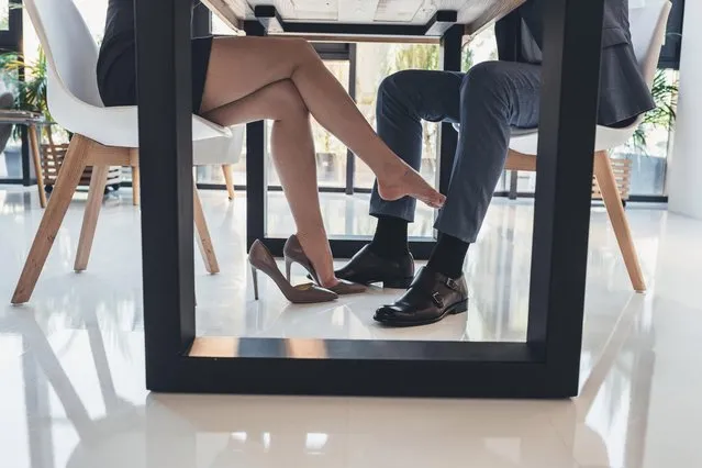 Cropped shot of a woman flirtatiously touching leg of man in a suit with her foot under the table. (Photo by LightField Studios/Skyfish Digital Media/Getty Images)