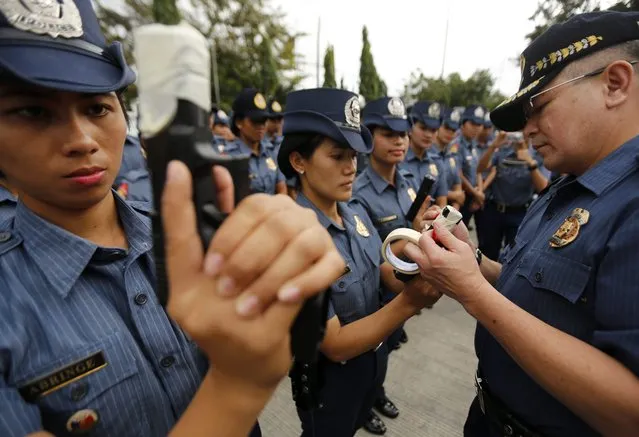 Filipino Police Regional Director Carmelo Valmoria (R)  tapes the muzzle of a gun at a police camp in Taguig City, south of Manila, Philippines, 22 December 2014. (Photo by Francis R. Malasig/EPA)