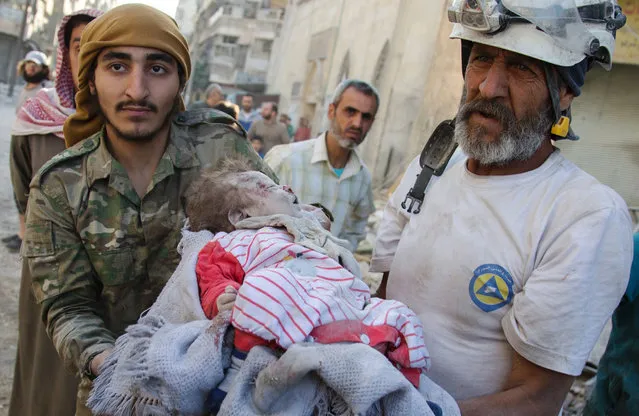 Members of the Syrian Civil Defence, known as the White Helmets, carry the body of a girl dug out from the rubble of a destroyed building following reported air strikes in the rebel-held Qatarji neighbourhood of the northern city of Aleppo, on October 17, 2016. (Photo by Karam Al-Masri/AFP Photo)