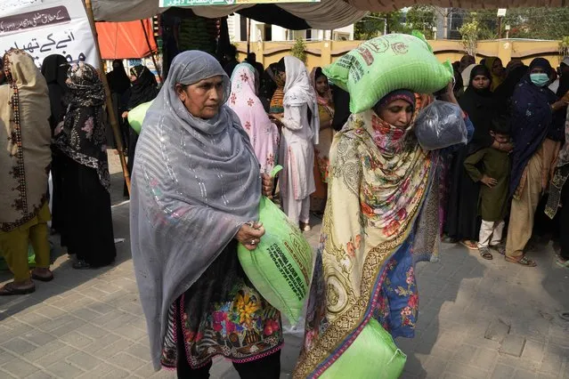 Women leave while others wait their turn to get a free sack of wheat flour at a distribution point, in Lahore, Pakistan, Thursday, March 30, 2023. Government is providing free flour to deserving and poor families during the Muslim's holy month of Ramadan due to high inflation in the country. (Photo by K.M. Chaudary/AP Photo)