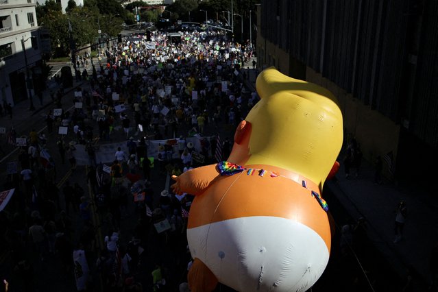 An inflatable balloon depicting U.S. President Donald Trump hovers above the crowd during a “No Kings” protest against U.S. President Donald Trump's policies, outside City Hall in Los Angeles, California, U.S., October 18, 2025. (Photo by Daniel Cole/Reuters)