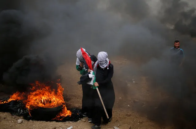Female Palestinian demonstrators walk past a burning tire during a protest demanding the right to return to their homeland, at the Israel-Gaza border, east of Gaza City, May 4, 2018. (Photo by Mohammed Salem/Reuters)