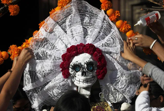 Residents work on a skeleton representation as part of the Day of the Dead festivities in Mexico City, Thursday, October 27, 2016. The holiday honors the dead as friends and families gather in cemeteries to decorate their loved ones' graves and hold vigil through the night on Nov. 1 and 2. (Photo by Marco Ugarte/AP Photo)