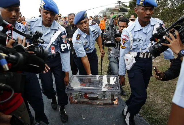 Military policemen carry the flight data recorder of AirAsia QZ8501 at the airbase in Pangkalan Bun, Central Kalimantan January 12, 2015. Indonesian navy divers on Monday retrieved the black box flight data recorder from an AirAsia airliner that crashed two weeks ago, killing all 162 people on board, a government official said. (Photo by Darren Whiteside/Reuters)