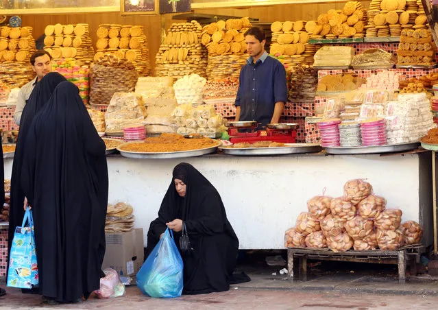 In this Thursday, January 8, 2015 photo, people shop at a store at the Shiite holy city of Najaf, 100 miles (160 kilometers) south of Baghdad, Iraq. Since Sunni militants of the Islamic State group overran large parts of Iraq, the country's most prominent Shiite cleric has fundamentally altered his spiritual role and has plunged straight into politics, weighing in to the government on policy and on fighting the extremists. (Photo by Hadi Mizban/AP Photo)