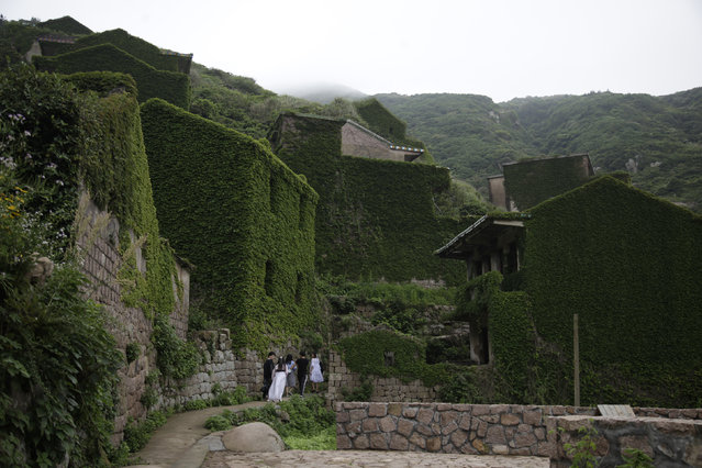 This May 19, 2018, photo shows tourists next to an abandoned building in the former fishing village of Houtouwan on the remote island of Shengshan, 90 kilometers off the coast of Shanghai. (Photo by Sam McNeil/AP Photo)