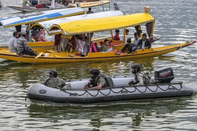 Tourists enjoy boat ride as Indian Navy's Marine Commandos patrol the Dal Lake ahead of G20 tourism working group meeting in Srinagar, Indian controlled Kashmir, Wednesday, May 17, 2023. (Photo by Mukhtar Khan/AP Photo)