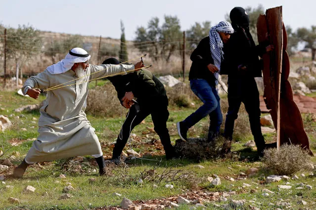 A Palestinian demonstrator uses a sling shot to hurl stones towards Israeli troops during a protest against Israeli settlements, in Deir Jarir in the Israeli-occupied West Bank on January 1, 2021. (Photo by Mohamad Torokman/Reuters)