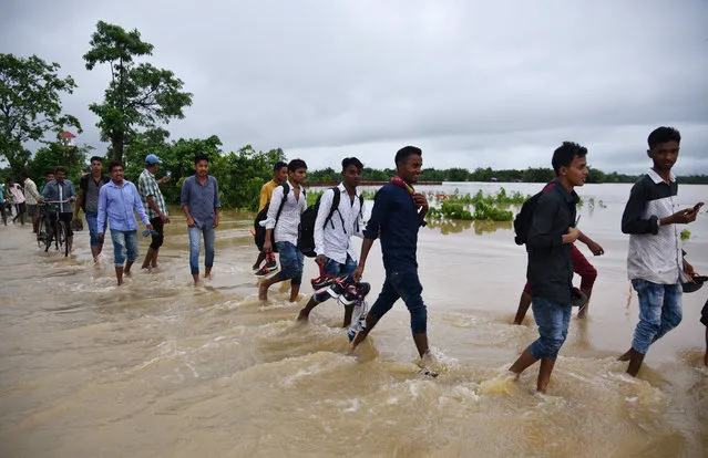 People wade through a flooded national highway after heavy rains in Golaghat district, in the northeastern state of Assam, India, June 13, 2018. (Photo by Anuwar Hazarika/Reuters)